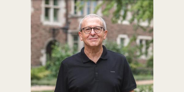 Head shot of Professor Mikhail Palatnik, wearing a black shirt, glasses. 