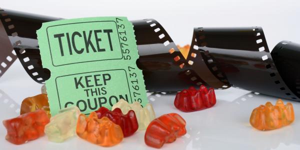 black film, movie tickets, and gummy bears on white background