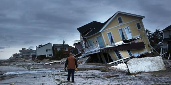 man walking in front of homes destroyed on shore after Hurricane Sandy
